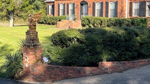 A brick house with a statue, well-maintained hedges, and a clear driveway.