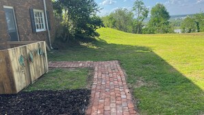 A brick pathway leading to a grassy area with a building in the background.
