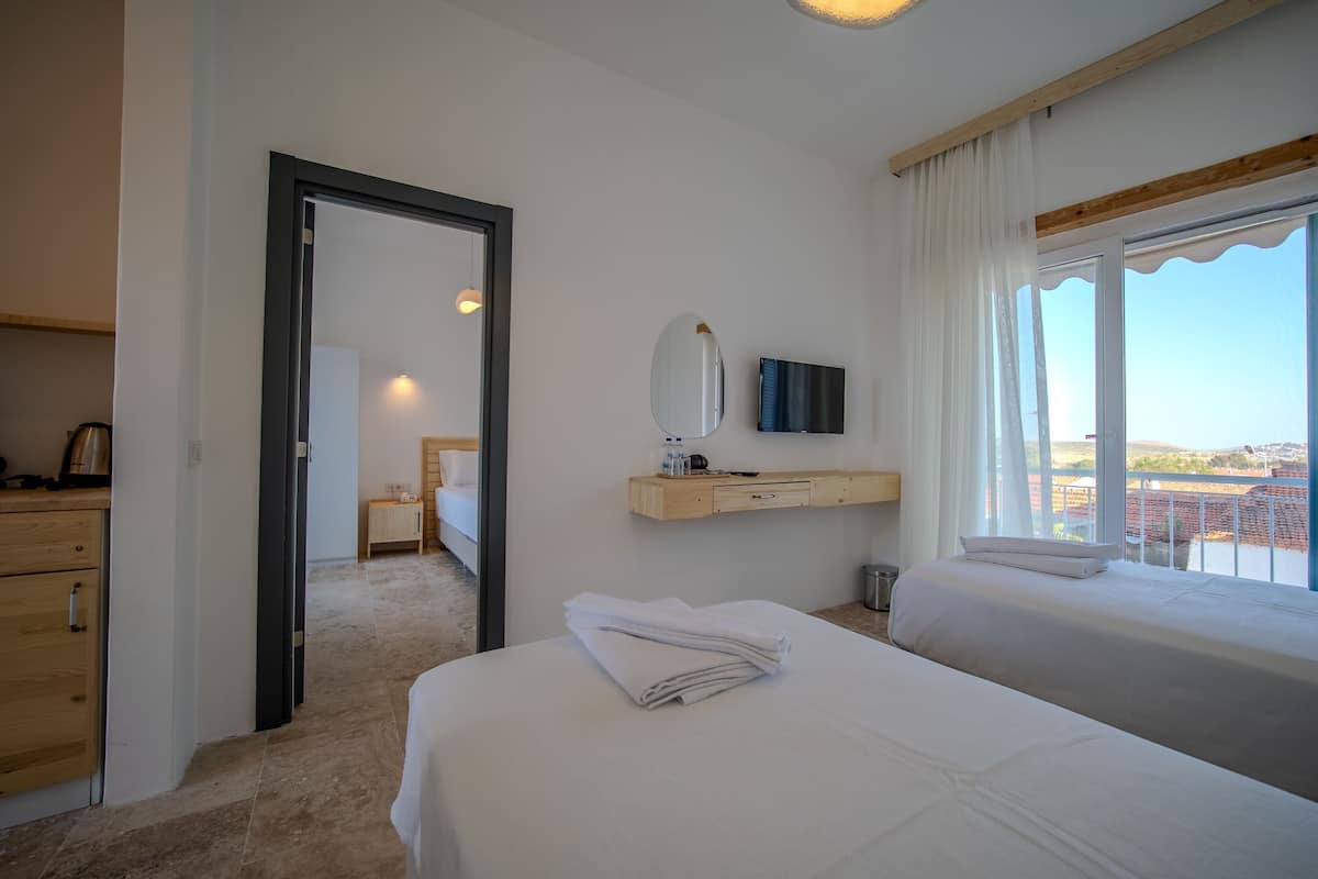 Habitación de hotel con dos camas, un aparador de madera, un televisor y una ventana con vistas.