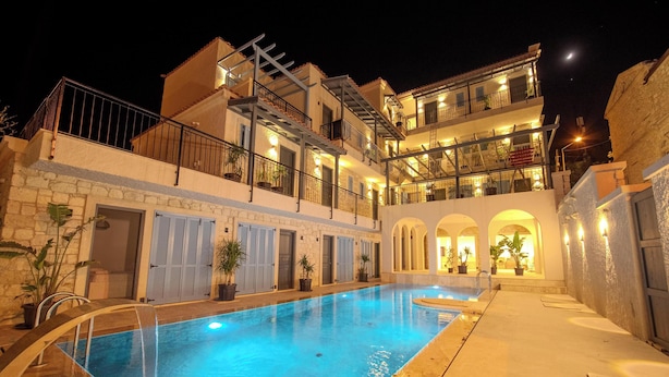 A hotel with a swimming pool, multiple balconies, and a stone facade. - Mia Storia Alaçatı Hotel (Cesme)