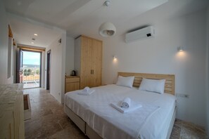 A bedroom with a large bed, wooden wardrobe, and a view through an open door. - Mia Storia Alaçatı Hotel (Cesme)