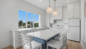A modern kitchen with a large island, white cabinetry, and pendant lighting. - Freshly Rebuilt Beach Escape — 4 Bedrooms, Pool & Island Vibes (Fort Myers Beach)