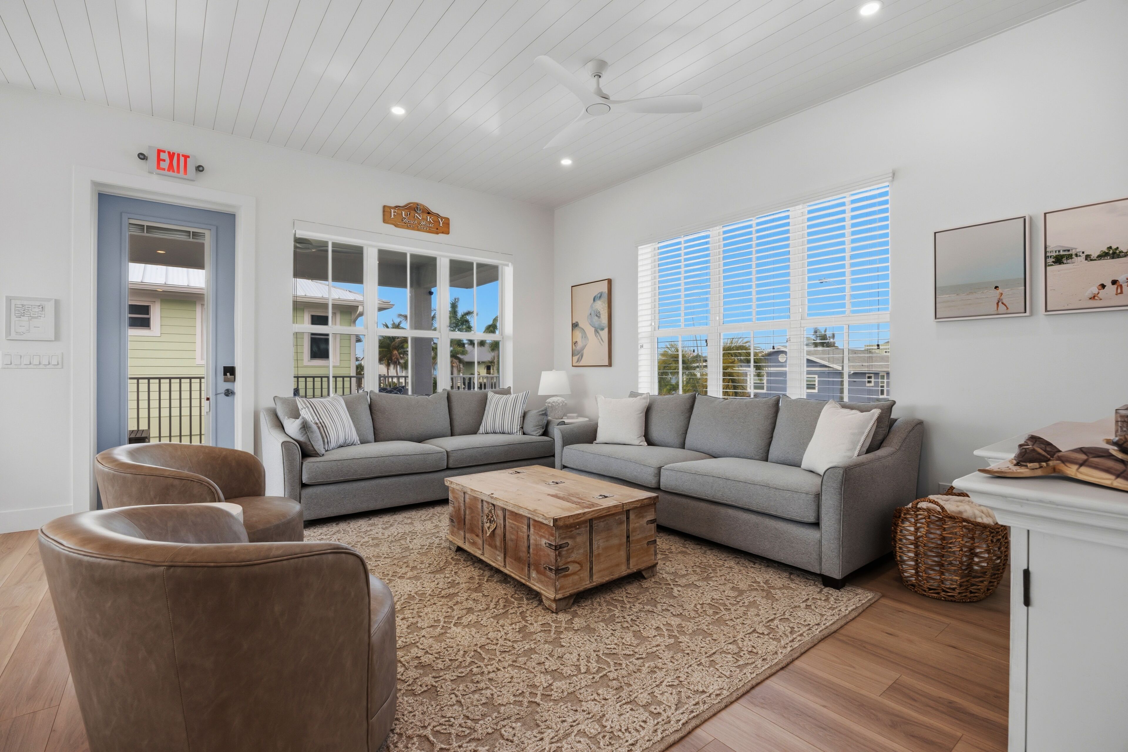 A living room with a sectional sofa, a wooden coffee table, and a large window with blinds.