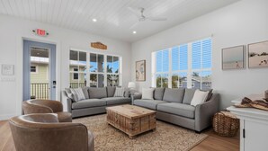 A living room with a sectional sofa, a wooden coffee table, and a large window with blinds. - Freshly Rebuilt Beach Escape — 4 Bedrooms, Pool & Island Vibes (Fort Myers Beach)