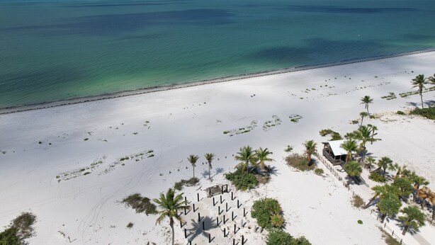 A beach with a white sand area, palm trees, and a small building. - Freshly Rebuilt Beach Escape — 4 Bedrooms, Pool & Island Vibes (Fort Myers Beach)
