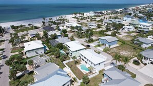 An aerial view of a coastal residential area with houses, a beach, and a clear view of the ocean. - Freshly Rebuilt Beach Escape — 4 Bedrooms, Pool & Island Vibes (Fort Myers Beach)