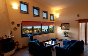 Un salon avec une cheminée, une vue sur la mer et un coin repas comprenant une table et des chaises.