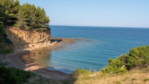 Un paysage côtier avec un ciel dégagé, une falaise rocheuse et une plage.