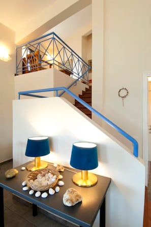 A staircase with blue railings, a table with two lamps, and a basket of eggs.