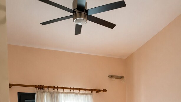 Une chambre d’hôtel avec deux lits, un ventilateur de plafond, une fenêtre avec des rideaux, une lampe de chevet et une porte.