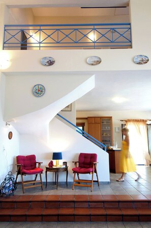 A staircase with a blue railing, red chairs, and a yellow dress in the background.