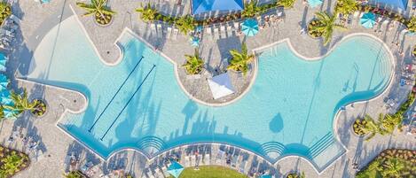 An aerial view of a resort with a large central pool, multiple smaller pools, and sun loungers.
