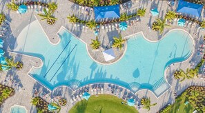 Eine Luftaufnahme eines Resorts mit einem großen zentralen Pool, mehreren kleineren Pools und Liegestühlen.