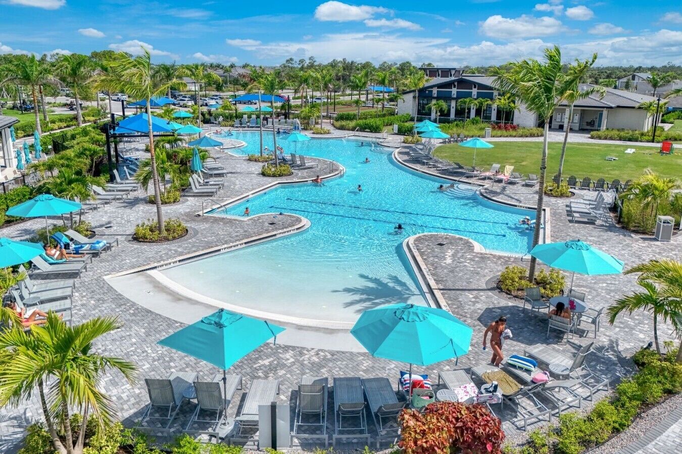 A resort with a large pool, lounge chairs, and umbrellas.