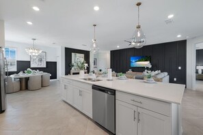 A modern kitchen with a large island, stainless steel appliances, and pendant lighting. - Luxe Golf Coach Home Near Venice Beach FL (Venice FL)