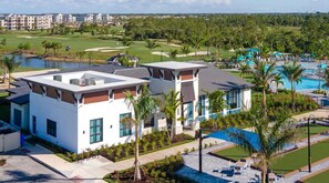 Ein modernes Hotel mit Pool auf dem Dach, einem Golfplatz im Hintergrund und einer gepflegten Landschaft.