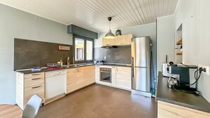 Moderni keittiö, jossa on sisäänrakennettu uuni, ruostumattomasta teräksestä valmistettu jääkaappi ja puukaapit.