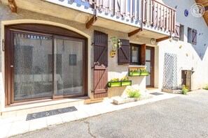 Ein Gebäude mit einer großen Schiebeglastür, Holzläden und einem Balkon mit Geländer.