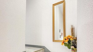 Uma escadaria com azulejos bege e um espelho com moldura dourada na parede.