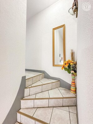Eine Treppe mit beigefarbenen Fliesen und einem goldgerahmten Spiegel an der Wand.
