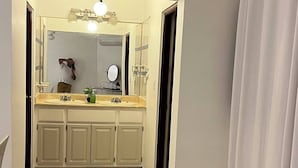 A bathroom with a sink, mirror, and cabinets. - The Distrito Atelier (Santo Domingo)