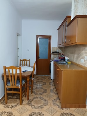 Una cocina compacta con una mesa de comedor, sillas, lavadora y baldosas de suelo estampadas.