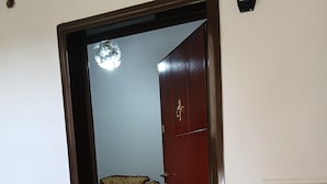 A doorway with a welcome mat, a potted plant, and a wall-mounted light fixture. - Enjoyable 1-bedroom apartment with AC in charming Berat (Berat)