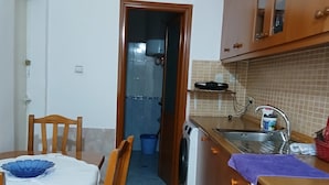 A compact kitchen with a dining table, chairs, a washing machine, and cabinets. - Enjoyable 1-bedroom apartment with AC in charming Berat (Berat)