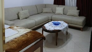 A living room with a sofa, a coffee table, a bed, and a ceiling fan. - Enjoyable 1-bedroom apartment with AC in charming Berat (Berat)