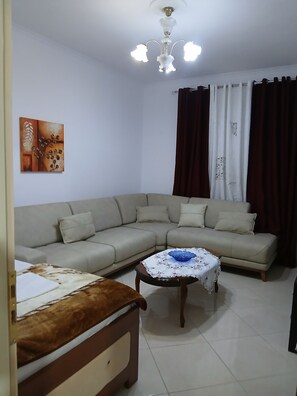 Una sala de estar con sofá, mesa de centro, cama y ventilador de techo.