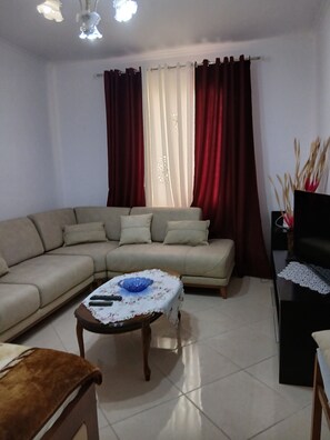 A living room with a sofa, a coffee table, and a TV stand. - Enjoyable 1-bedroom apartment with AC in charming Berat (Berat)