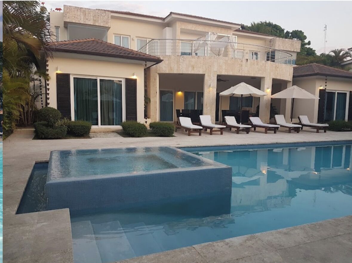 Une maison moderne dotée d’une piscine, de chaises longues et d’un espace salon extérieur abrité.