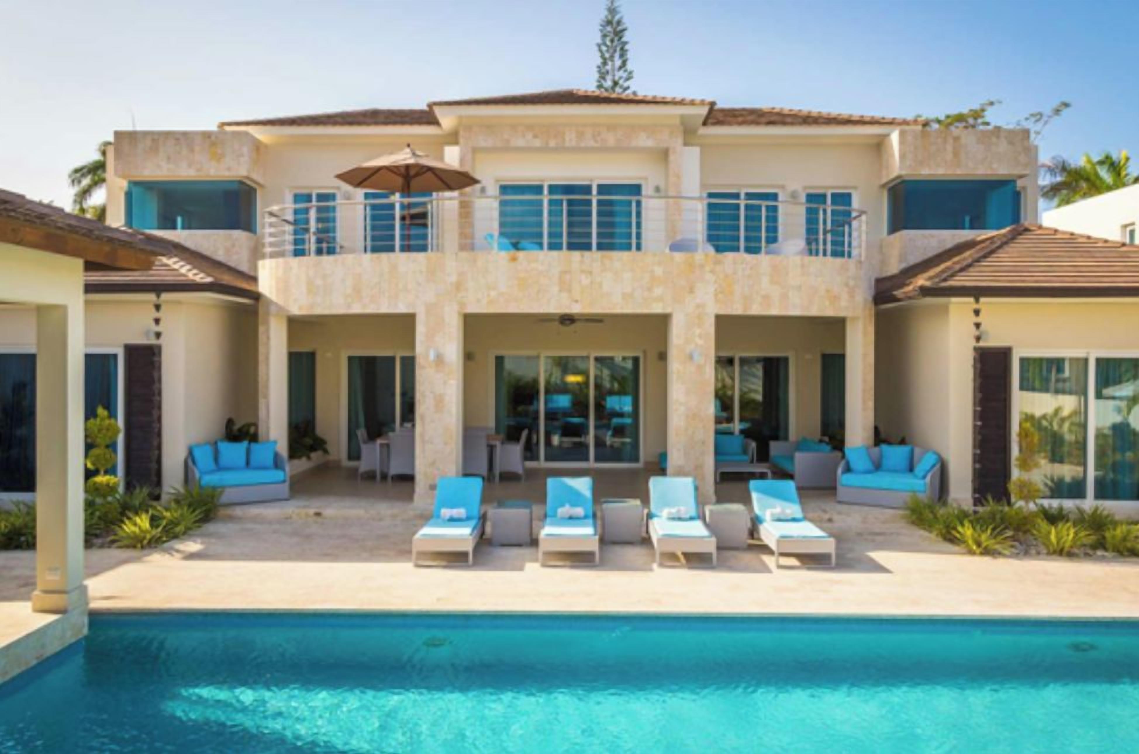 A two-story house with a swimming pool, outdoor seating, and a garage.