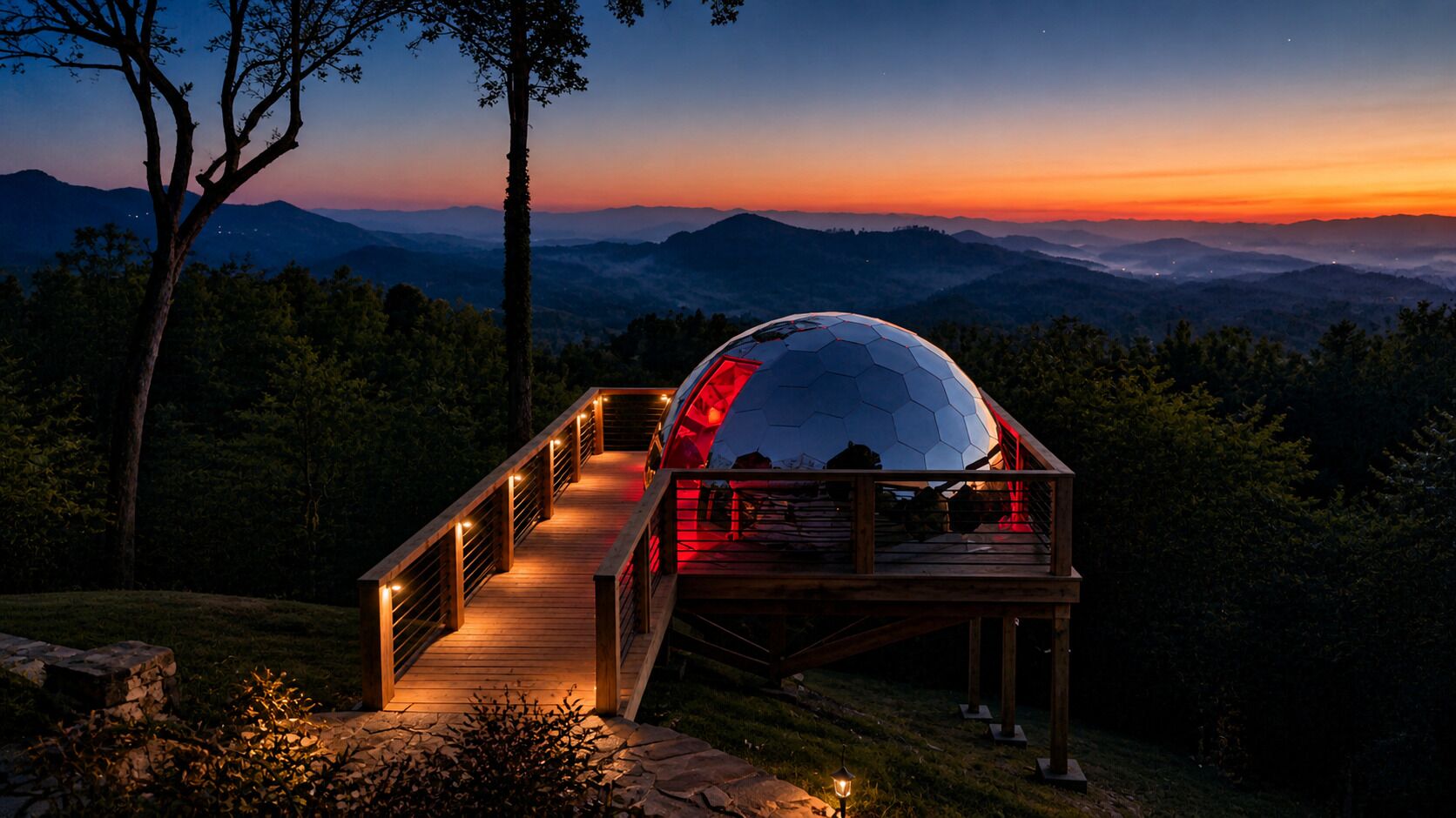 Una estructura abovedada con cubierta y barandilla de madera, rodeada de un paisaje montañoso al anochecer.