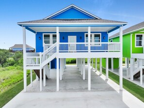 Ein blaues Haus mit Veranda, weißen Geländern und einem Betonweg.