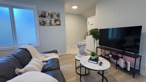 Uma sala de estar moderna com um sofá, uma mesa de centro, uma televisão e uma pequena cozinha.