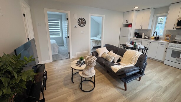 Um apartamento moderno com sala de estar, área de jantar, cozinha compacta e um quarto.