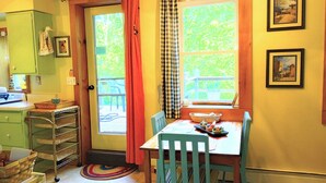 Une cuisine avec une table, des chaises, une fenêtre avec des rideaux et une porte.