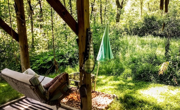 Una hamaca bajo una estructura de madera en un bosque verde y frondoso.
