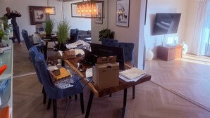 Ein modernes Wohnzimmer mit Essbereich, einem großen Fernseher und einer Chandelüster.