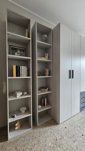 Ein Zimmer mit eingebautem Bücherregal, einem Kleiderschrank mit Spiegel und einem kleinen Rundtisch.