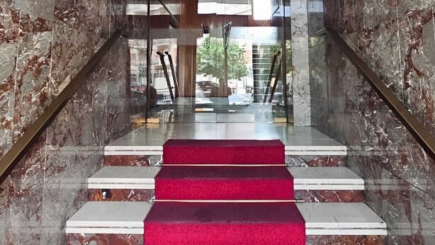 A marble staircase with red carpeted steps leading to a glass door. - CASA GB - Your home in the center of Turin (Torino)
