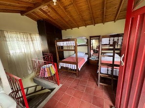 Une chambre de dortoir avec des lits superposés, un escalier en métal rouge et un sol carrelé.