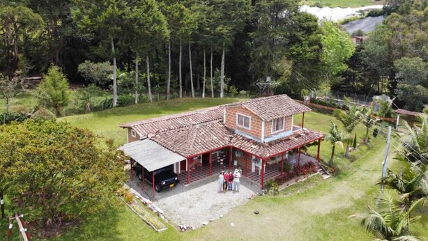 A house with a red roof, a covered porch, and a small garden.
