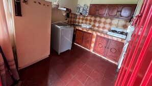 A compact kitchen with a washing machine, wooden cabinets, and a tiled backsplash.