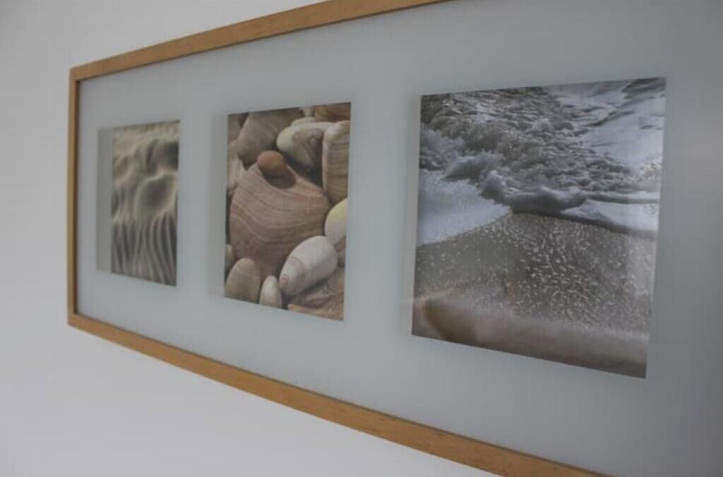 Une œuvre d’art encadrée, composée de trois panneaux, est accrochée à un mur.