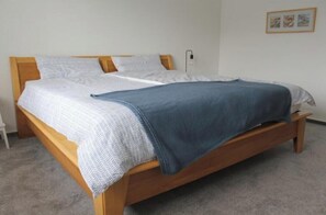 Ein Einzelbett mit Holzrahmen, weißer Bettwäsche und einer blauen Decke.