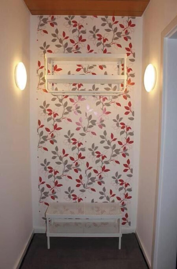 Ein Flur mit floralem Wandpapier, einer weißen Bank und zwei Wandleuchten.