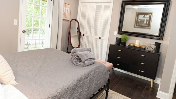 A bedroom with a bed, a dresser, a mirror, and a door. - Fabulous 5-bedroom house with AC in charming Chickamauga (Chickamauga)