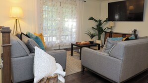 A living room with a sofa, a coffee table, a TV, and a ceiling fan. - Fabulous 5-bedroom house with AC in charming Chickamauga (Chickamauga)